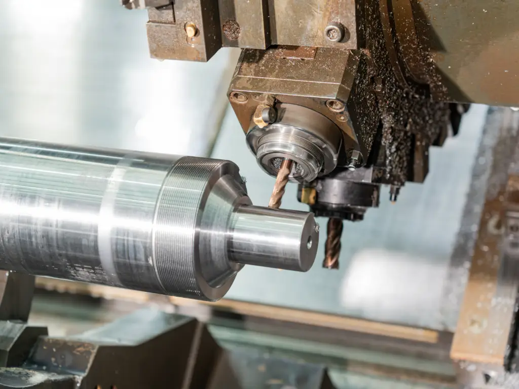 Close-up of a precision lathe machining the surface of a cylindrical workpiece, producing fine metal chips.