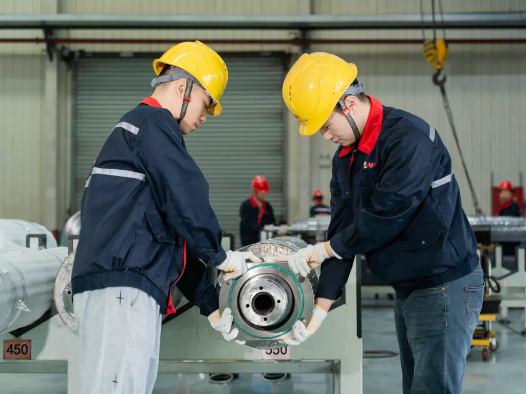 Technicians fitting securement components onto a corrugated roll as part of the installation process on a manufacturing line.