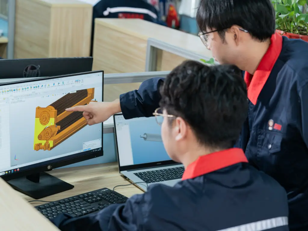 Engineers at RMM employing CMATLAB 5.0 to simulate and analyze the performance of a corrugated roll design displayed on a computer.