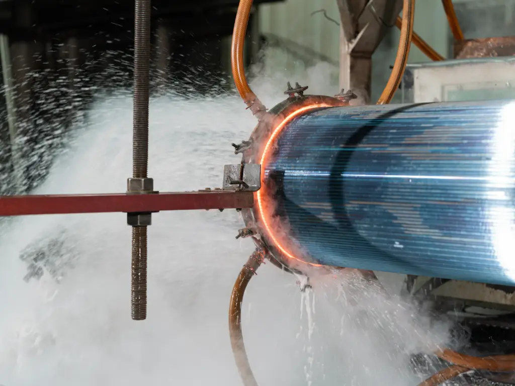 Close-up of the quenching process at RMM, showing a hot corrugated roll entering a cooling bath with intense steam rising.