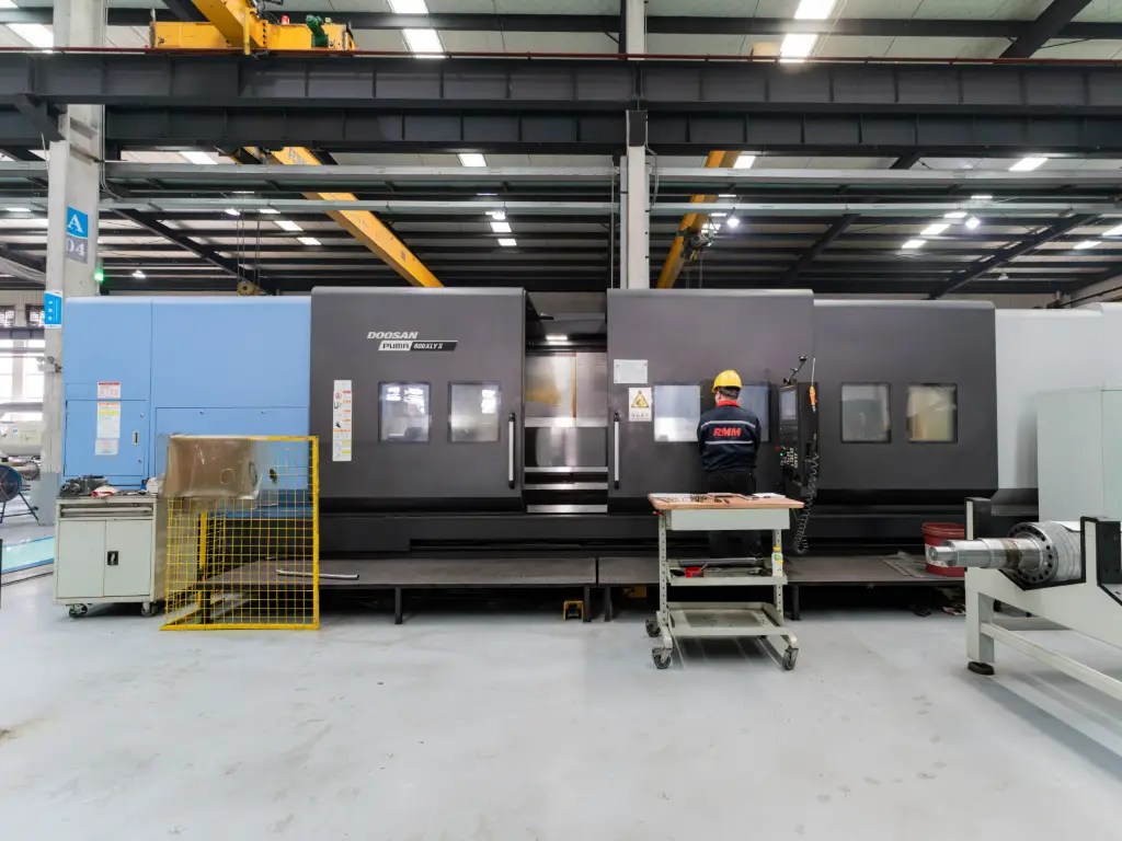 A worker operates a large, gray Doosan Puma 3100 ULY mill-turn center in the RMM factory
