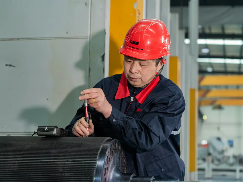 Technician using digital durometer showing 338 HB hardness reading on metal surface